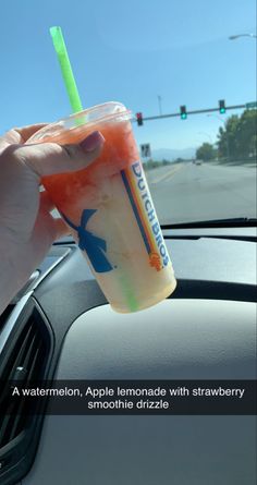 a hand holding an apple lemonade with strawberry smoothie on the side of the road