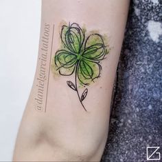 a small green flower tattoo on the right arm and leg, with watercolors