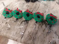 three green and red christmas ornaments sitting on top of a marble table next to other items