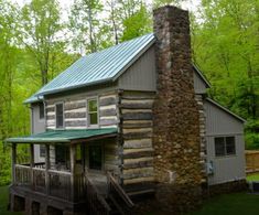 a log cabin sits in the woods next to a stone fire hydrant and deck