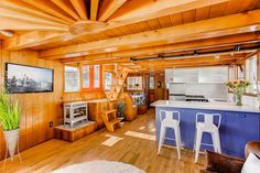 a kitchen and living room with wood paneling on the walls, hardwood floors and ceiling