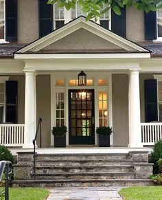 a house with black shutters and white trim on the front door, steps leading up to it