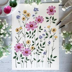 a painting with flowers on it next to paintbrushes and watercolor paints,