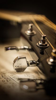 a close up of a guitar's knobs and strings on a sheet of music