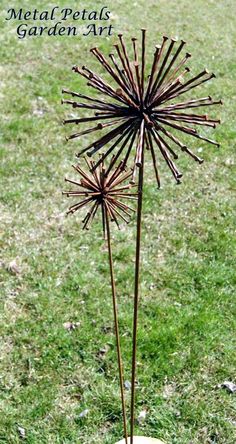 a metal sculpture on top of a rock in the middle of a grass field with text overlay that reads metal petals garden art