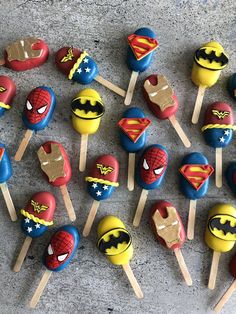 the cake pops are decorated like superheros and have different designs on them with wooden sticks