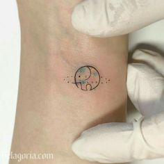 a small elephant tattoo on the left side of the arm, with stars and dots around it