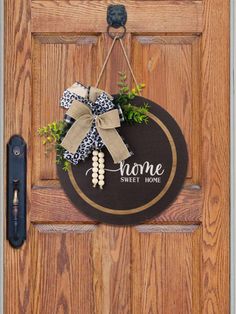 a door hanger that says home sweet home with a bow hanging on the front door