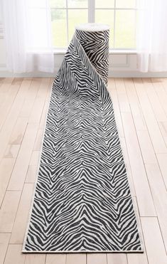 a black and white zebra print rug on the floor in front of a large window