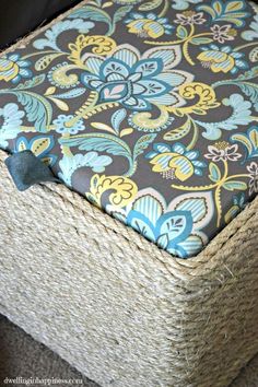 an upholstered ottoman with blue, yellow and green flowers on it's cushion