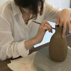 a woman is making a vase out of clay