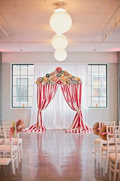 an empty room with red and white striped drapes on the ceiling, decorated for a wedding ceremony