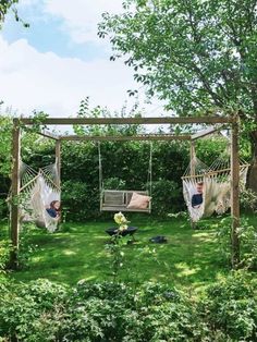 two hammock chairs sitting in the middle of a lush green field