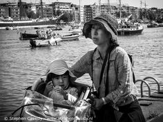 a black and white photo of a woman with a child in a stroller by the water