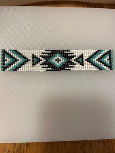 a beaded bracelet with blue and white designs on it, sitting on top of a table