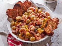 a white plate topped with corn and shrimp next to french toast on top of a wooden table