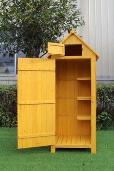 a yellow wooden cabinet sitting on top of a lush green field