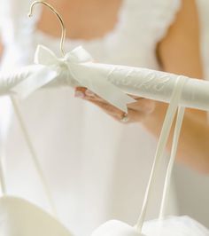 the bride is holding her white wedding dress with a bow on it's back