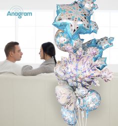 a man and woman sitting on a couch with balloons in the shape of snowflakes