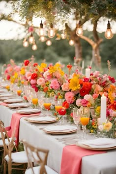 a long table is set with flowers and candles for an outdoor dinner party or reception