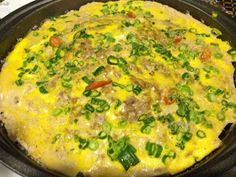 an omelet with meat and vegetables in a skillet on the stove top