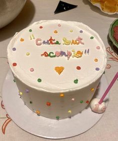 a white cake with confetti on it sitting on a table