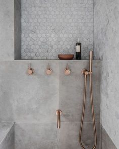 a shower with copper faucets and soap dispensers on the wall