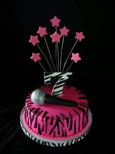 a zebra print cake decorated with pink stars and a microphone in the shape of z