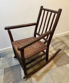 a wooden rocking chair sitting on top of a tiled floor