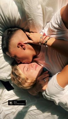 a man and woman laying in bed with their heads close to each other as they cuddle