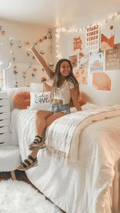 a woman sitting on top of a bed in a room with white walls and lights