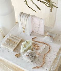 a table topped with jewelry on top of a white counter next to a vase filled with flowers