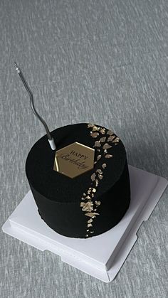 a black and gold decorated cake with a toothbrush in it's mouth on top of a white plate