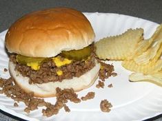 a hamburger and some chips on a paper plate