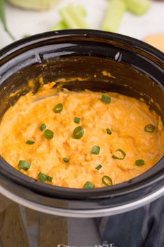 a crock pot filled with cheese and green onions