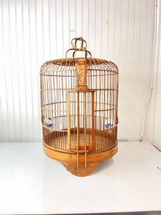 a birdcage sitting on top of a white table next to a wooden shelf