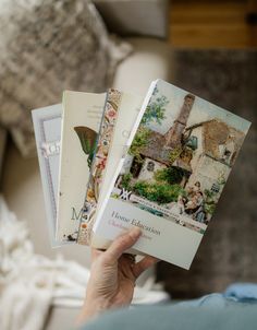 a person holding three books in their hands