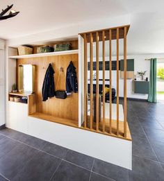 a coat rack with coats hanging on it in a room that has tile floors and white walls