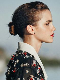 a woman with her hair in a high bun is looking off into the distance while wearing a black floral blouse