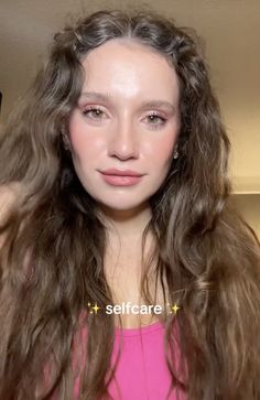 a woman with long brown hair is looking at the camera