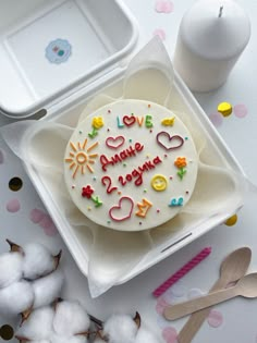 a birthday cake sitting on top of a white plate next to cotton and spoons