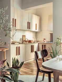 an open kitchen and dining room area with wooden flooring, white walls, and cabinets