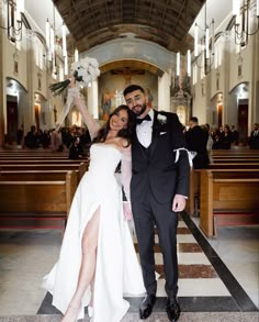 a bride and groom pose for a photo in front of pews at a church