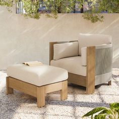 a chair and ottoman sitting on top of a gravel covered ground next to a wall