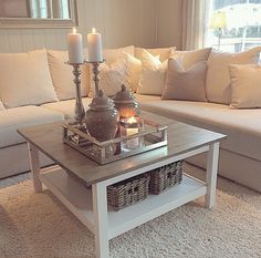 a living room filled with white furniture and candles on top of a coffee table in front of a couch