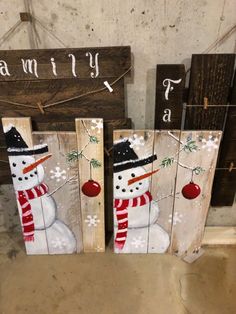 three snowmen painted on wooden planks in front of a sign that says family