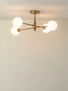 three light brass ceiling fixture with white glass globes on the top and bottom part