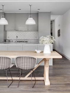 two chairs sit at a table in the middle of a room with gray walls and wooden flooring