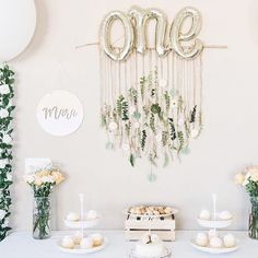 a table topped with lots of cakes and cupcakes next to balloons that say one