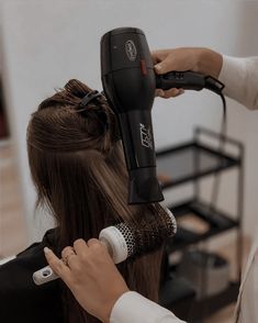 a woman is blow drying her long hair